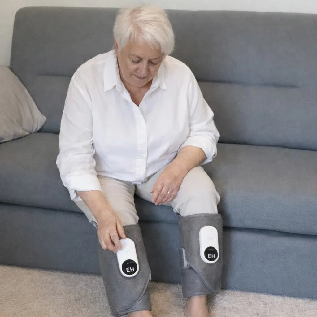 Older woman in white shirt adjusting Recovie leg massager wraps on both calves